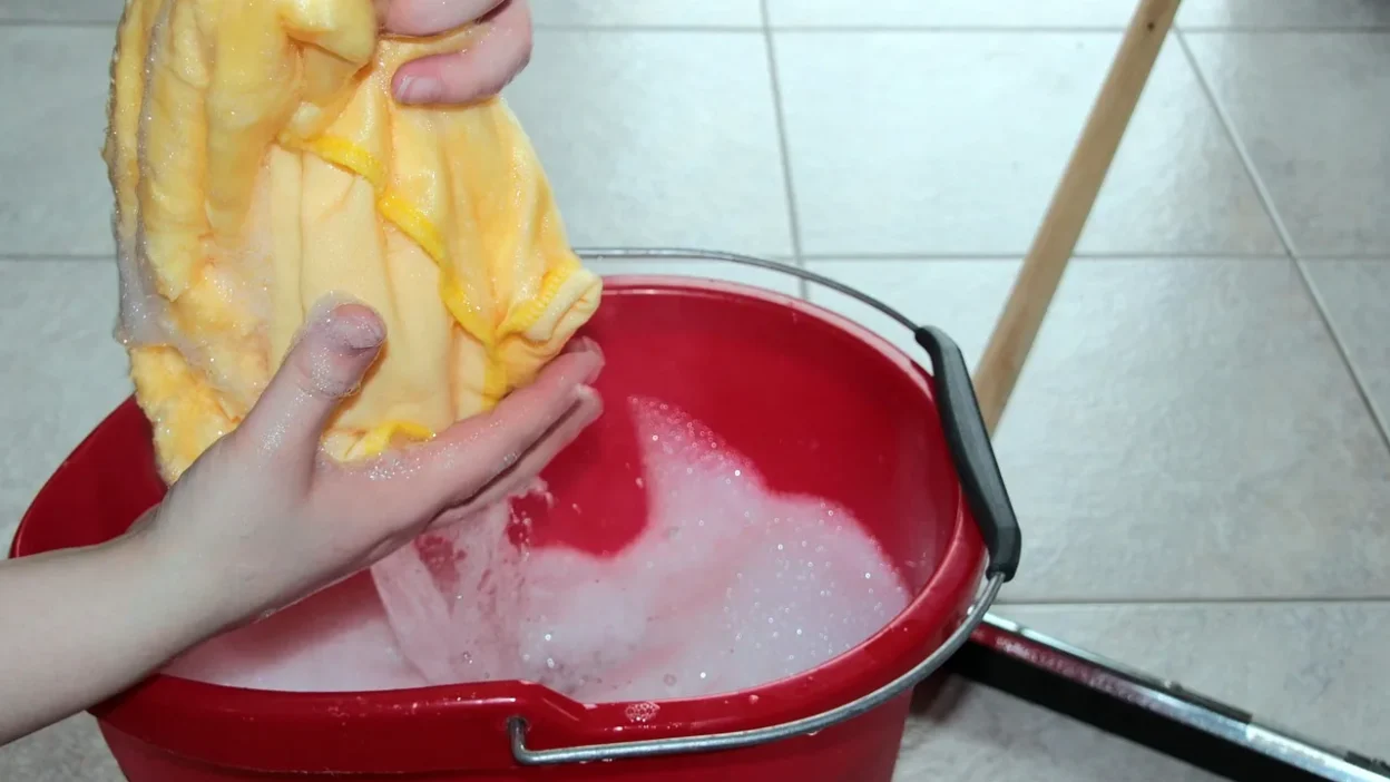 A person cleaning different floor types: ceramic tile, vinyl plank, and wood-look laminate with appropriate tools.
