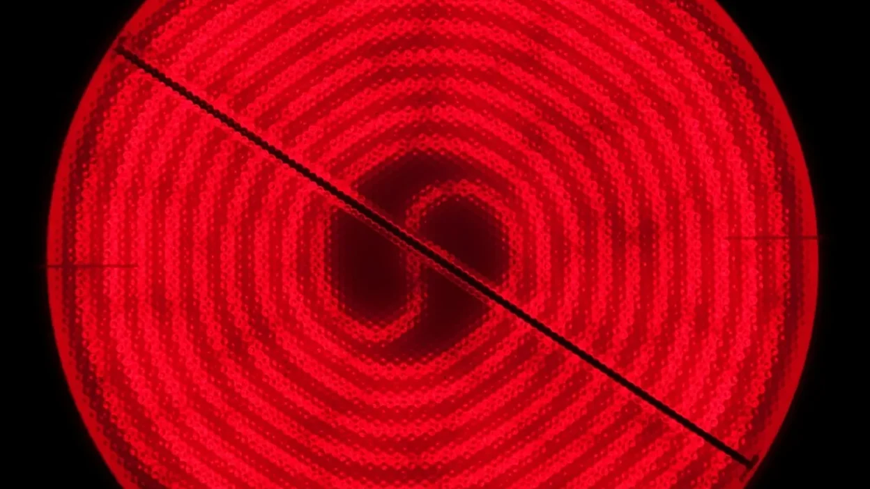 Close-up of stubborn grease smears on a glass stovetop with a cleaning spray bottle nearby.