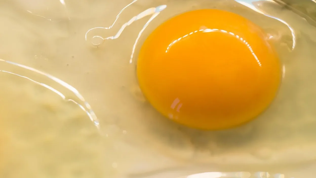 A person using a microfiber cloth and natural degreaser spray to clean greasy kitchen stovetop.