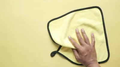 A microfiber cloth and a roll of paper towels side by side on a clean kitchen countertop.