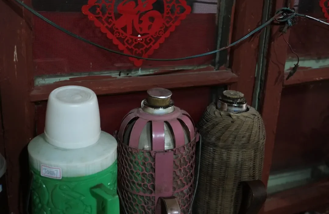 A person holding a spray bottle and cloth, confused by unlabeled cleaning supplies on a cluttered shelf.