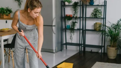 Person using too much water while mopping a hardwood floor, causing potential water damage.